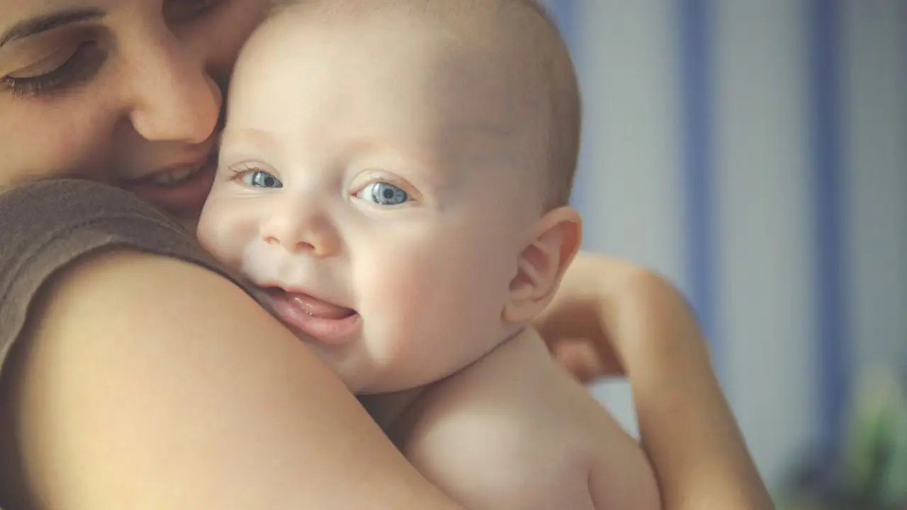 Nowy urlop dla mam i ojców - mama przytula noworodka i uśmiecha się