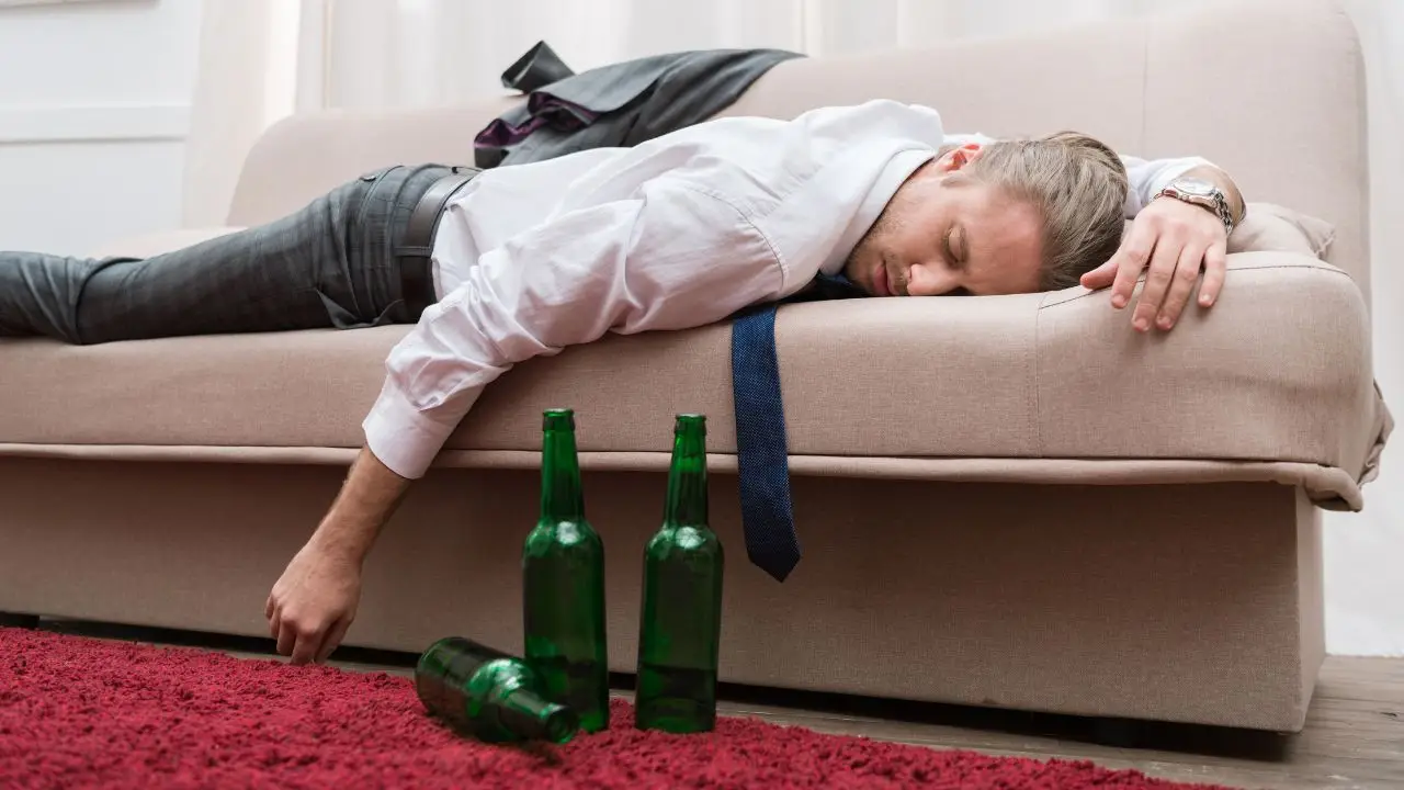 Alkohol wśród pracowników - dane ZUS - mężczyzna pijany na kanapie śpi