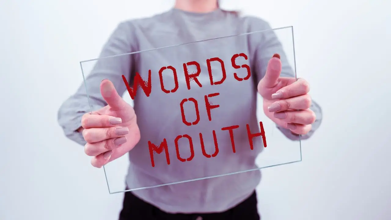 Przeklinanie w pracy - osoba trzymająca w dłoniach pleksi z napisem "words of mouth"