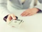 Renta wdowia - zbliżenie kobiecych rąk trzymających pieniądze w dolarach amerykańskich