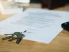 Umowa najmu okazjonalnego na stole, na niej klucze, obok kalkulator