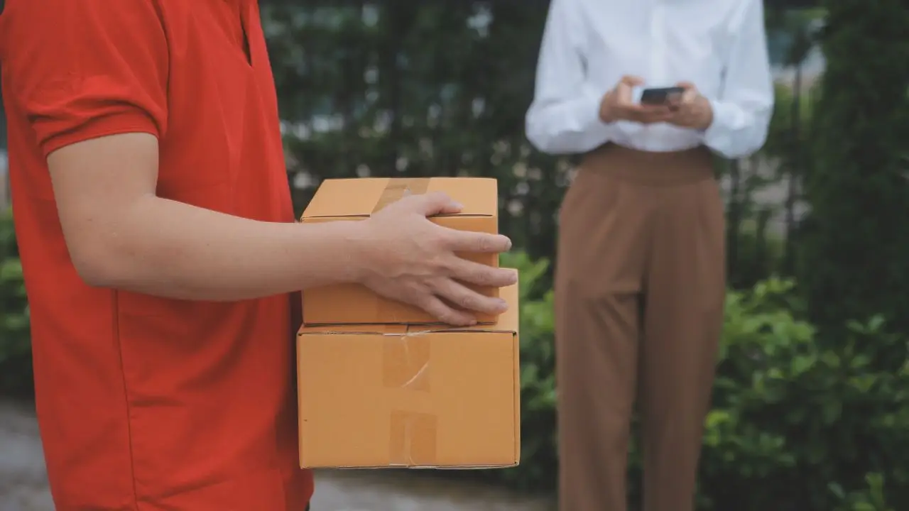 Zwolnienia DHL - kurier trzymający paczki w dłoniach