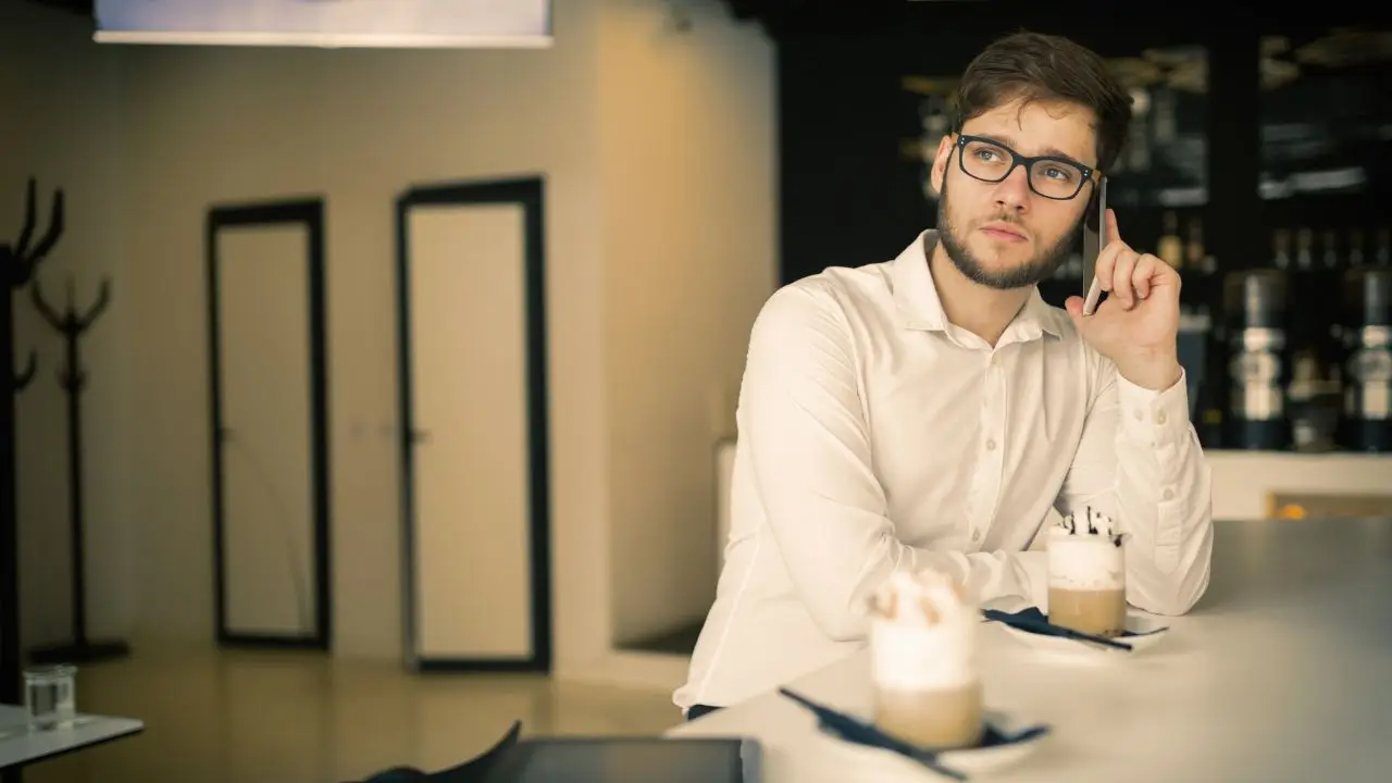 Dobrowolny ZUS - mężczyzna w kawiarni rozmawiający przez telefon przedsiębiorca