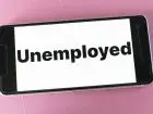 Zwolnienia w Polsce - napis unemployed na telefonie