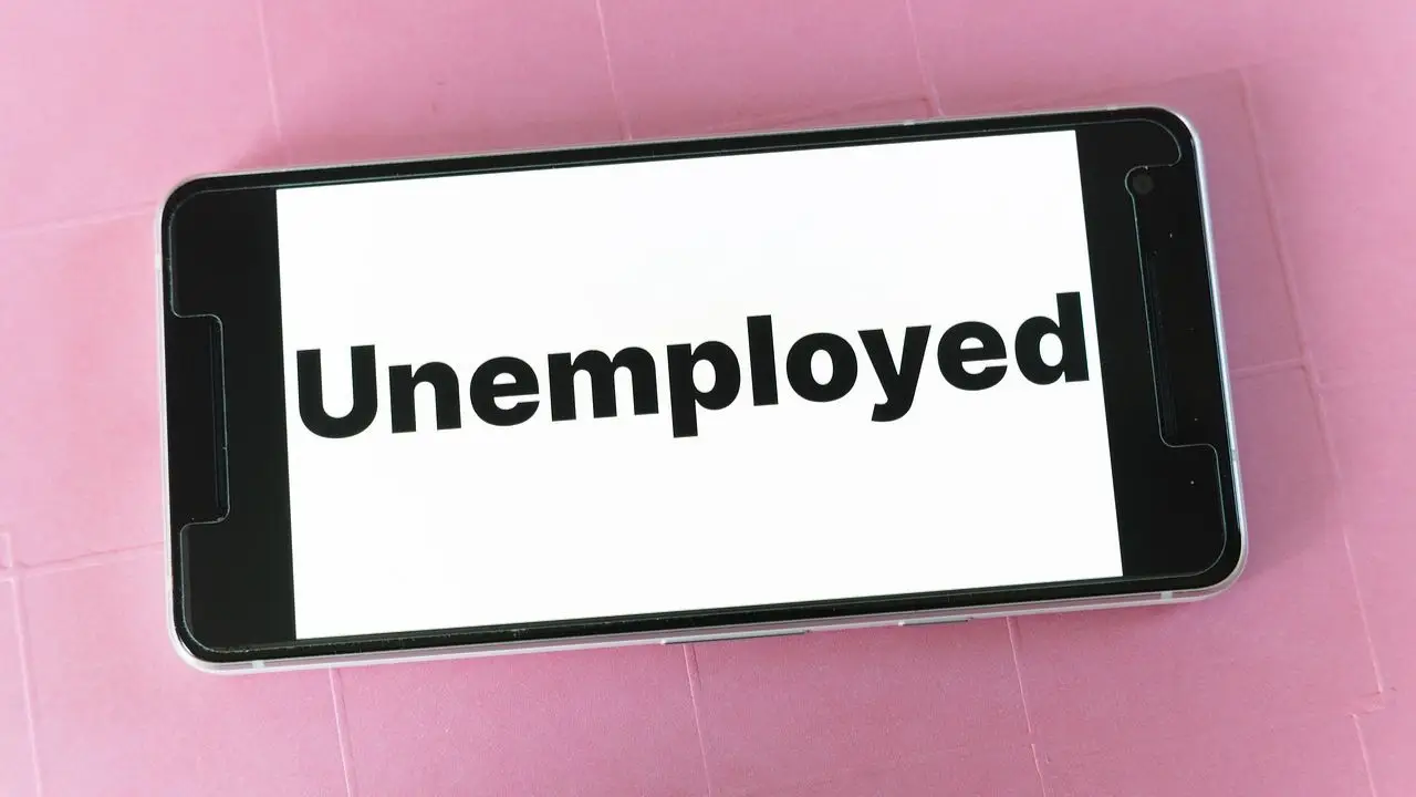 Zwolnienia w Polsce - napis unemployed na telefonie
