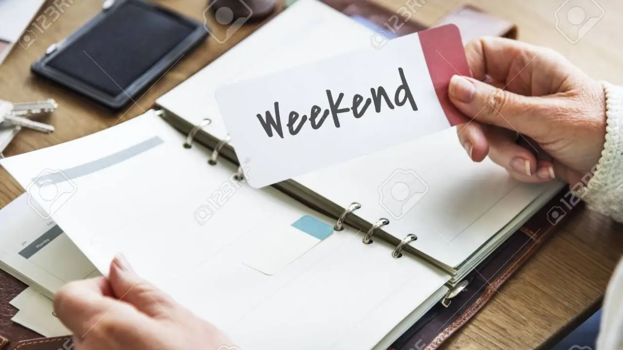 4-dniowy tydzień pracy pilotaż - napis weekend trzymany w dłoni osoby sprawdzajacej kalendarz