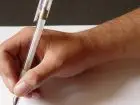 Czynny żal - osoba pisząca na kartce, zbliżenie na dłoń