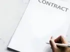Umowa przedwstępna - kartka z napisem contract i dłoń osoby składającej podpis