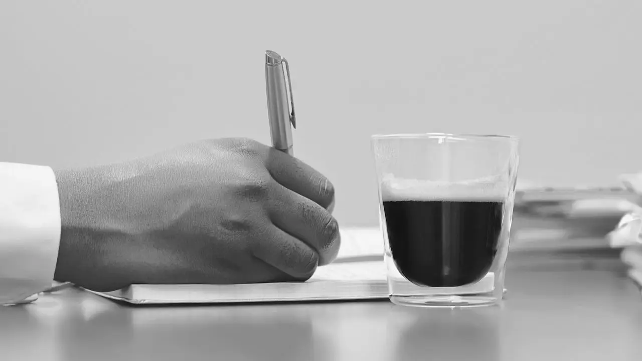 Księgowy - dłoń z długopisem i kawa na blacie
