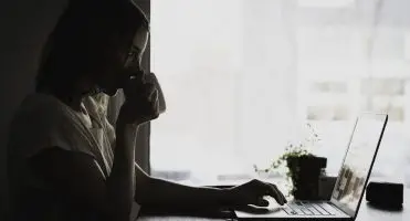 Praca zdalna co to - kobieta pijąca z kubka przy laptopie