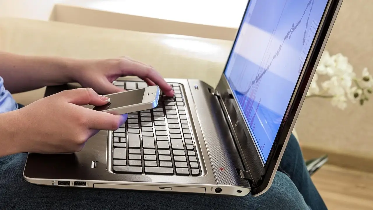 Telepraca - osoba pracują przy laptopie z telefonem w dłoni
