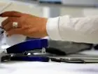 VAT-R - dłoń osoby pracującej w biurze i przybory biurowe