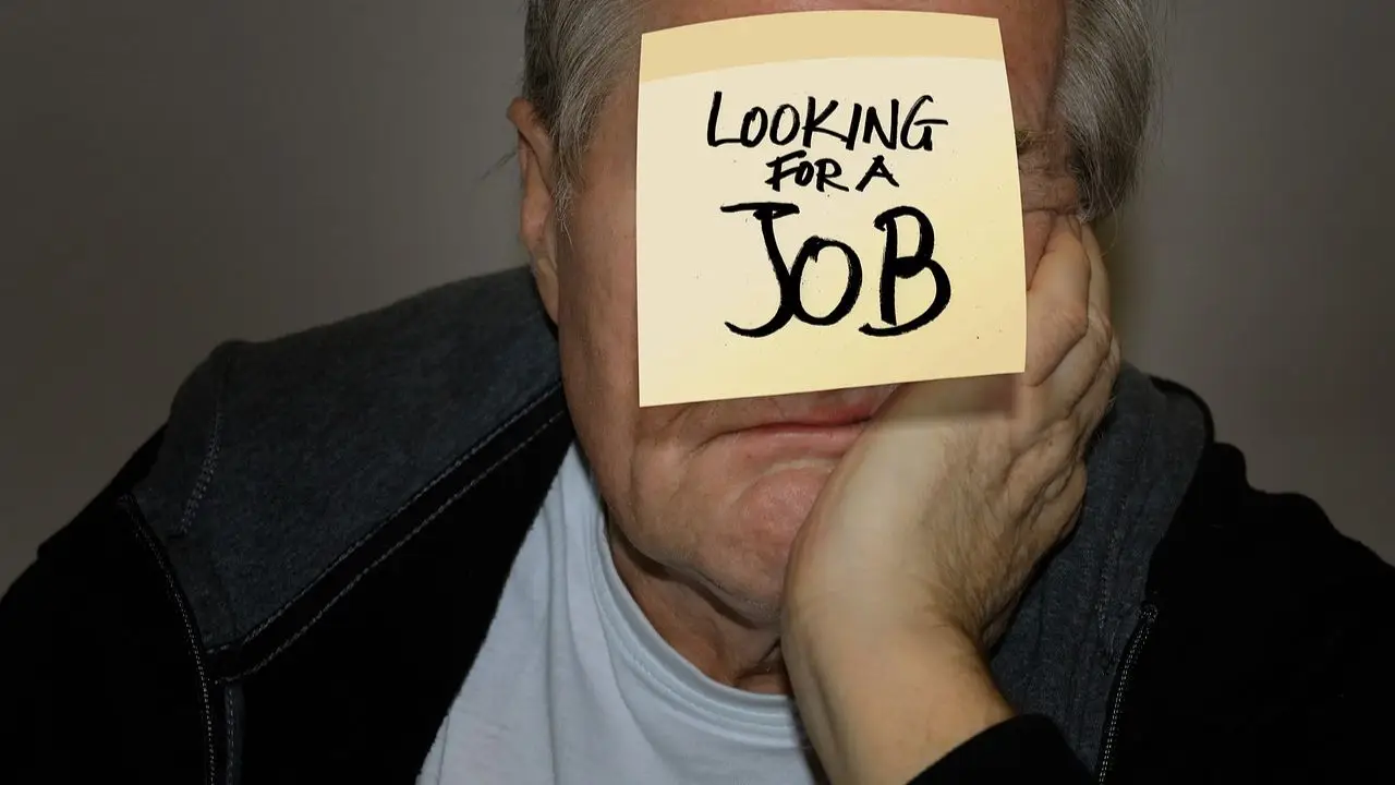 Mężcyzzna z kartą z napisem looking for a job na twarzy
