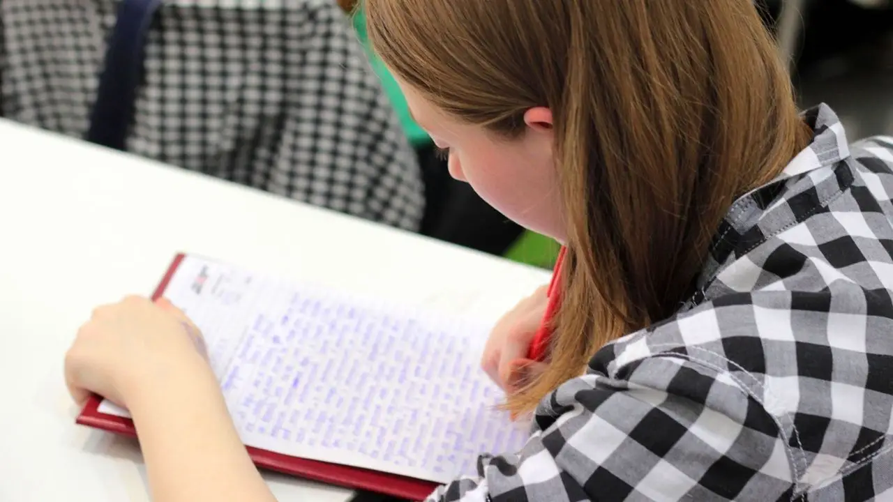 Praca dla studenta - kobieta notująca w zeszycie