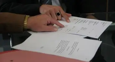Przedłużenie umowy o pracę - zbliżenie na dłonie dwóch osób omawiających dokumenty