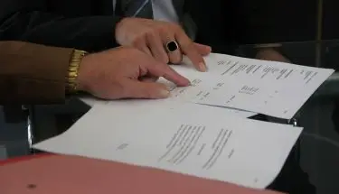 Przedłużenie umowy o pracę - zbliżenie na dłonie dwóch osób omawiających dokumenty