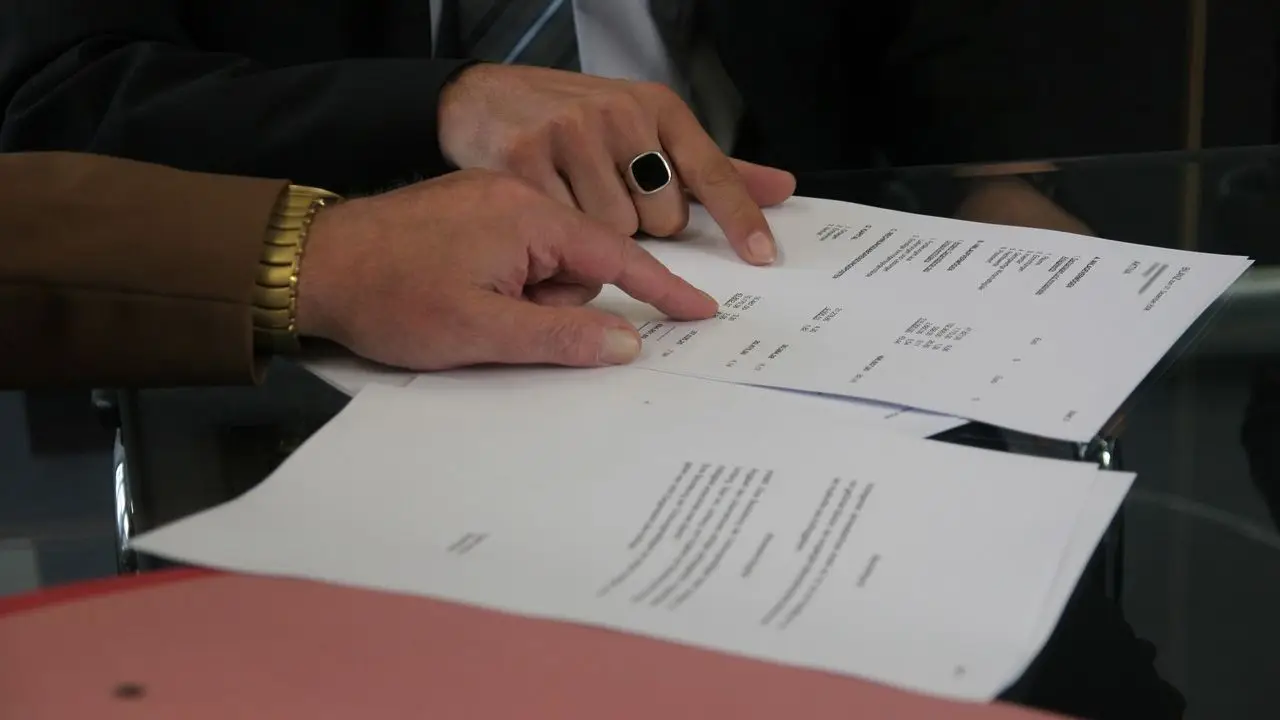 Przedłużenie umowy o pracę - zbliżenie na dłonie dwóch osób omawiających dokumenty