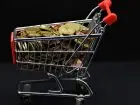 Najniższa krajowa netto styczeń 2026 - miniaturowy wózek sklepowy z monetami w środku
