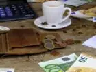 Minimalna stawka na zleceniu 2023 - monety, banknoty, kawa, portfel i kalkulator na stole