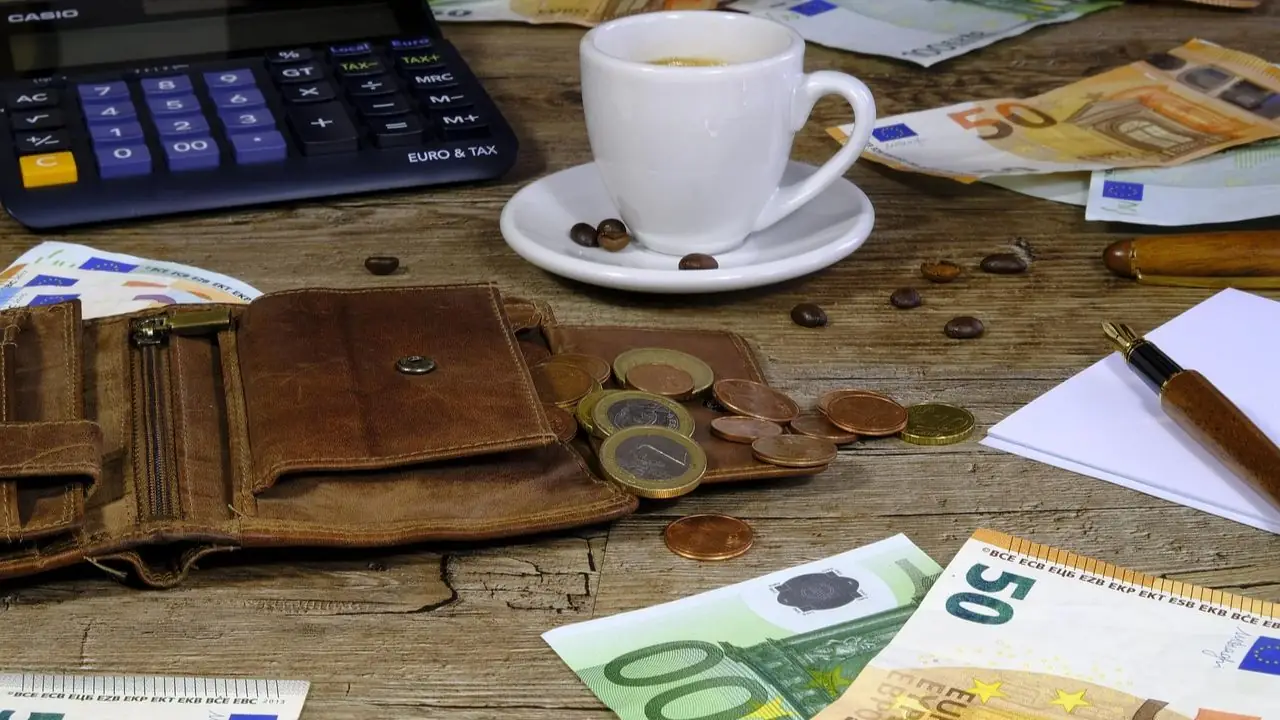 Minimalna stawka na zleceniu 2023 - monety, banknoty, kawa, portfel i kalkulator na stole
