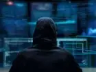 Dark web - osoba w kapturze przed wieloma monitorami