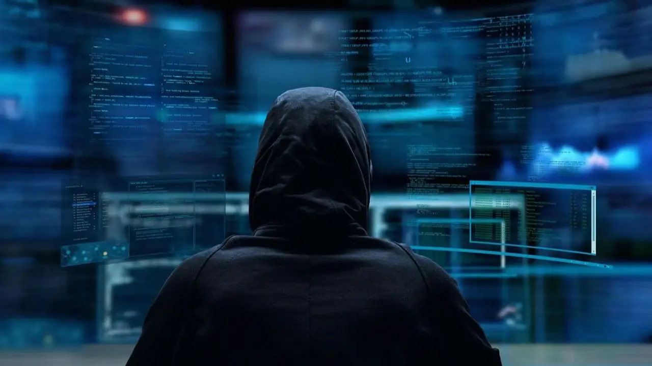 Dark web - osoba w kapturze przed wieloma monitorami