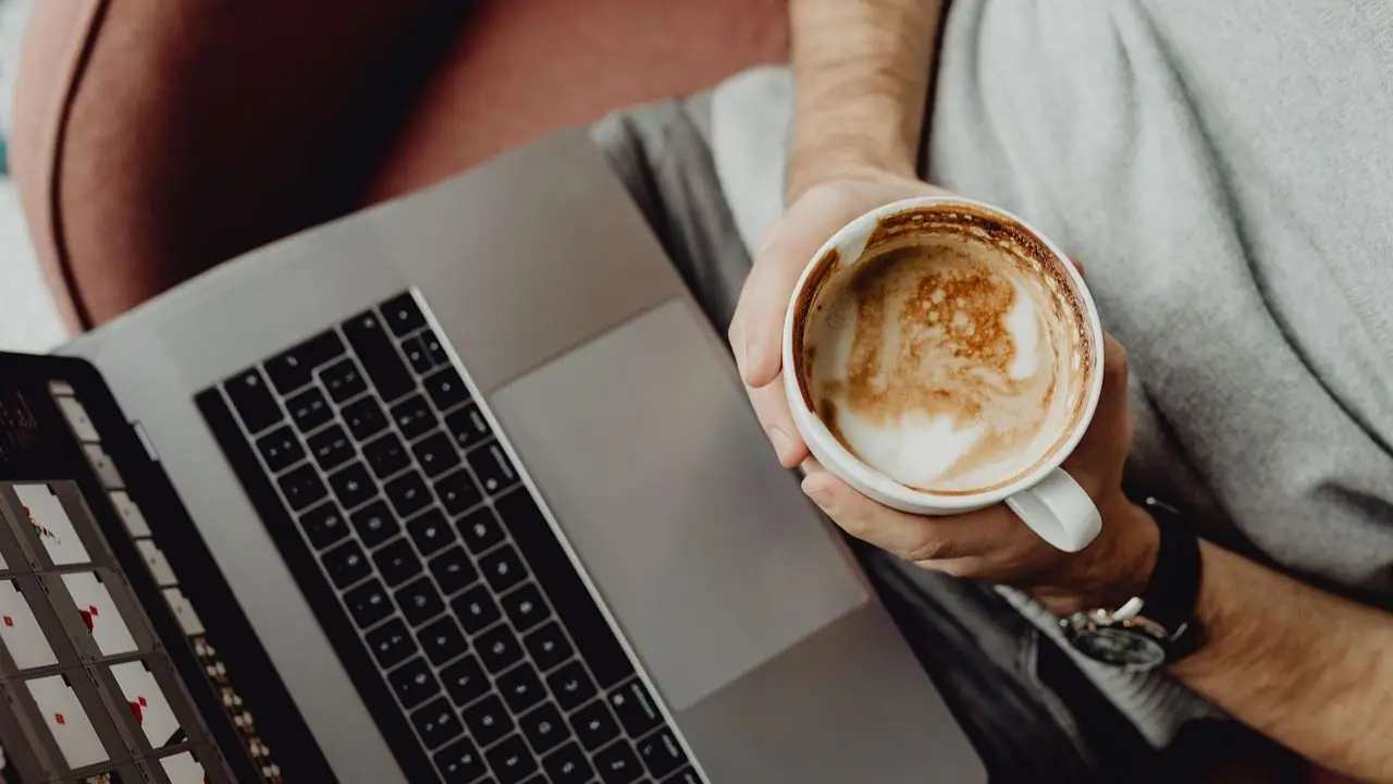 Home office - co to - kawa w dłoni przy laptopie